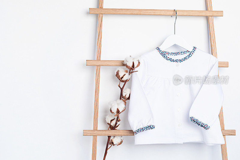 Cute newborn clothes hanging on the rack. Organic cotton baby apparel mockup.
